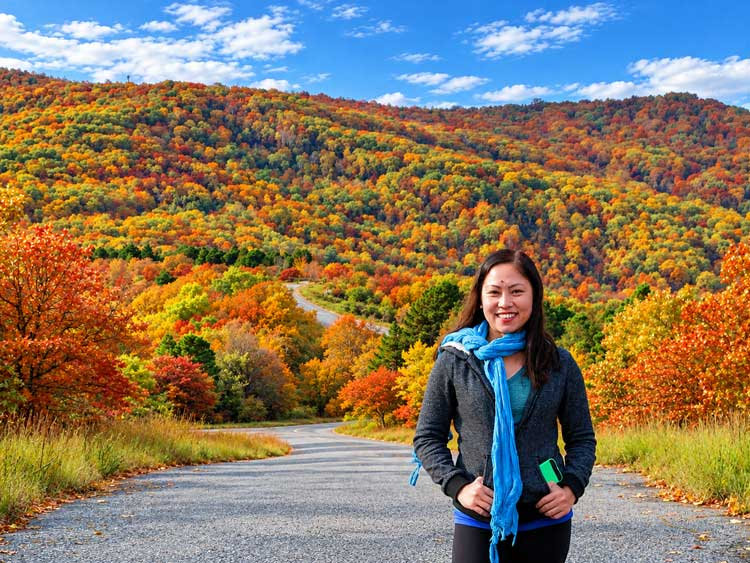 Cavanal Hill Fall Colors: Driving Oklahoma'S &Quot;World'S Highest Hill&Quot; Standing On The Cavanal Hill Road In Poteau, Oklahoma, With A Ridge Of Orange, Gold, And Green Fall Foliage Behind Her